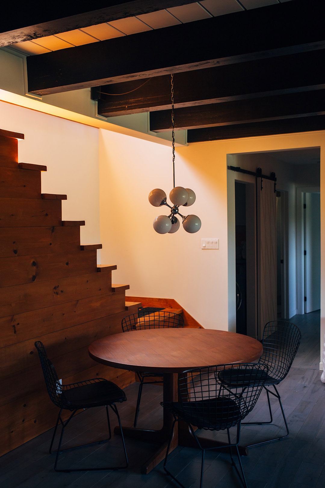 Jo Residence - Interior shot - wood stairs, exposed beams, and small round table.